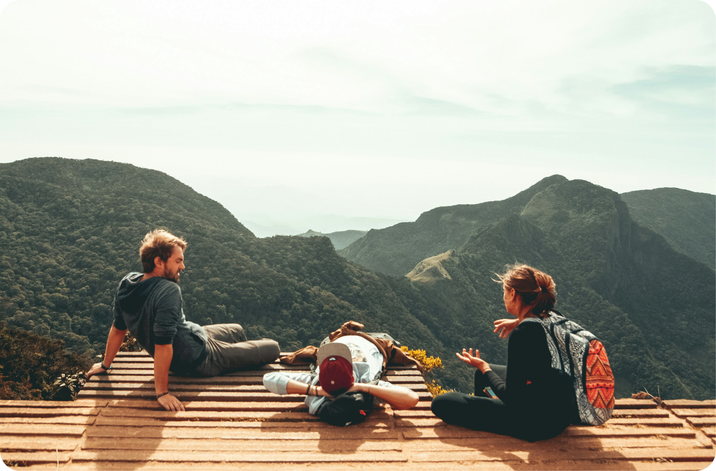 Three travelers resting together on a mountain viewpoint
